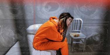 Woman sitting with her hands on her head, in jail 