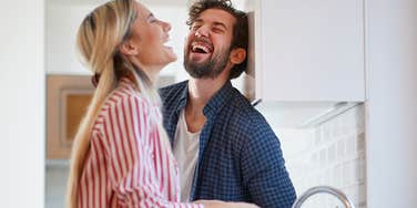 man and wife laughing together in the kitchen